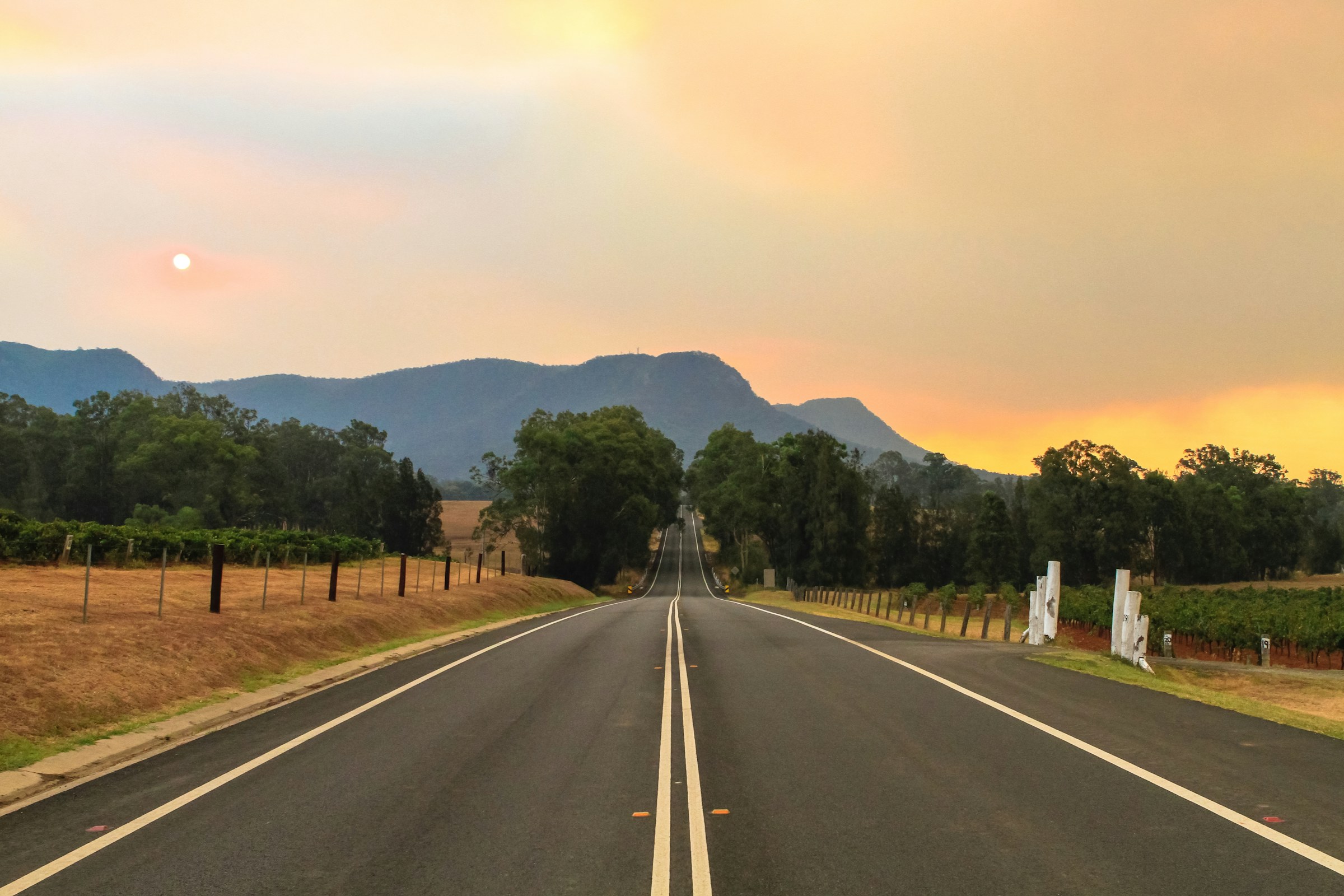 Regional road running toward a mountain range at dusk